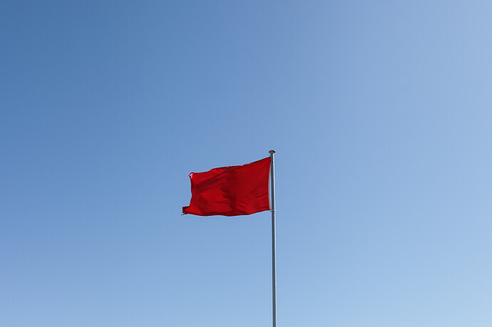 Red flag on a pole, against a blue sky