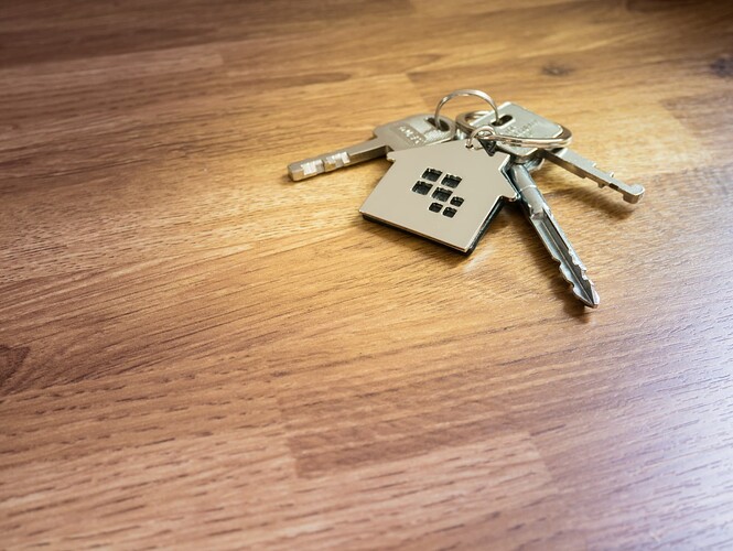 A set of keys with a house keyring placed on a wooden table top