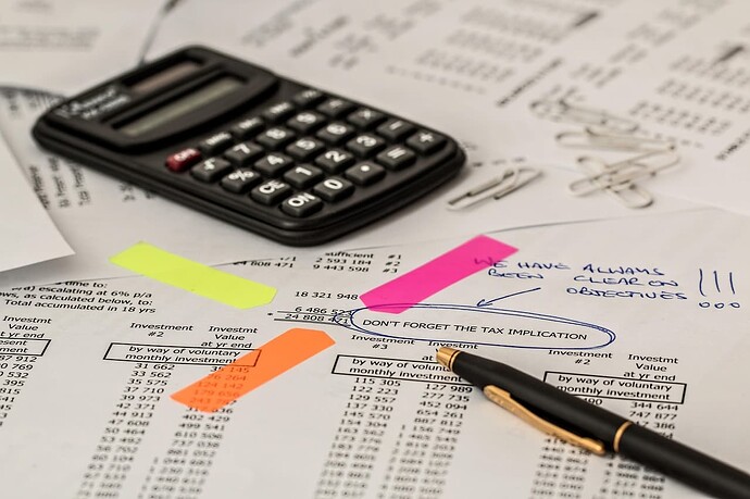 A calculator, pen, and paper with financial calculations and notes about tax implications suggest a focus on investment and financial planning