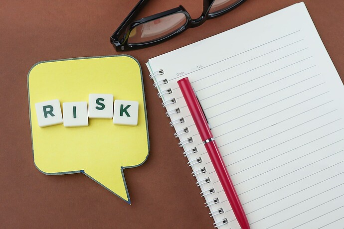 Letter cubes spelling "Risk" on a sticky note next to a notepad