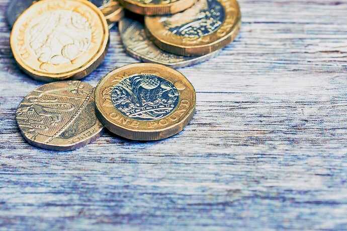 British pound coins, fifty pence and twenty pence, placed on a wooden surface, to represent "lending"