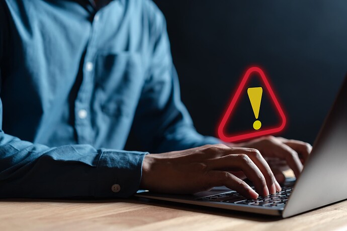 Warning sign over a user typing on a laptop keyboard
